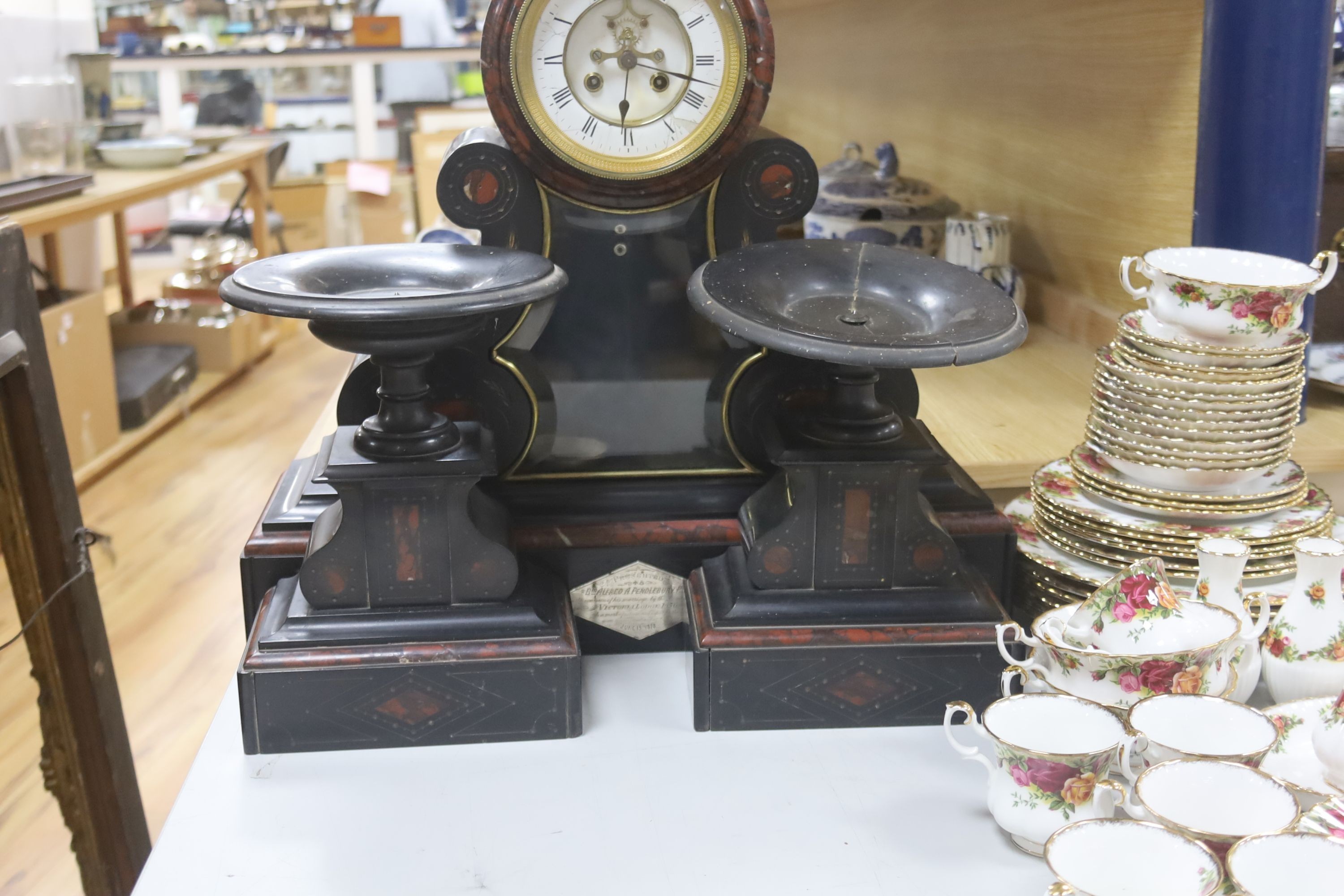 A 19th century Victorian slate clock garniture, the movement with visible Brocot escapement with key and pendulum (af), clock 49cm high